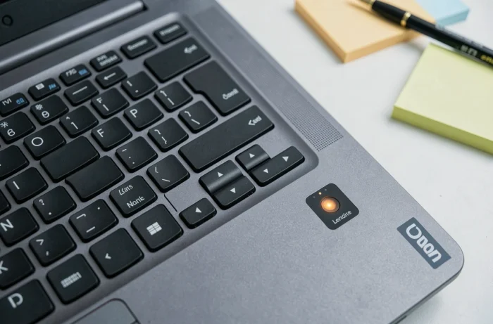 Gros plan sur le bouton power et le voyant LED clignotant d'un ordinateur portable Lenovo posé sur un bureau blanc